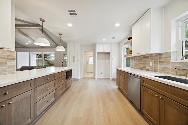 kitchen with stainless steel appliances, sink, light hardwood / wood-style flooring, white cabinets, and pendant lighting