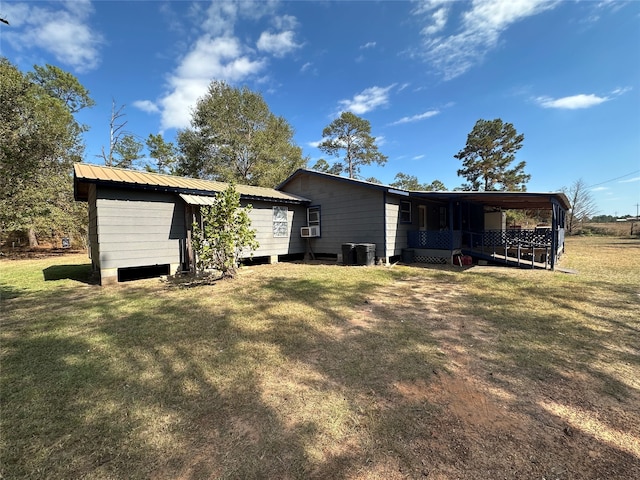 back of house with a carport, cooling unit, and a lawn