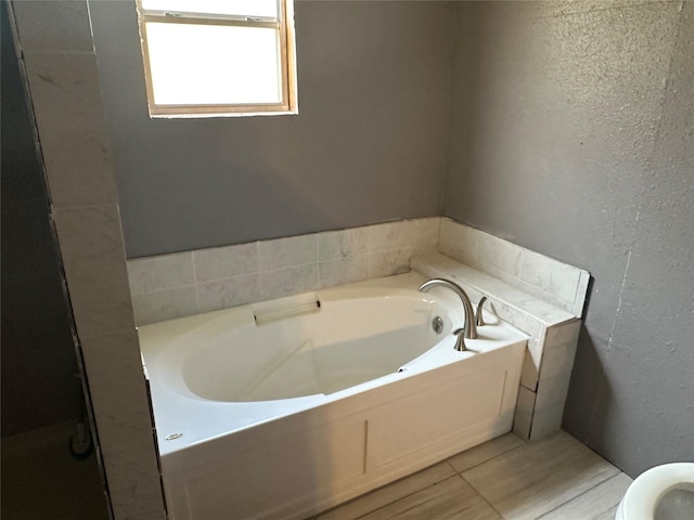 bathroom with a tub to relax in and toilet