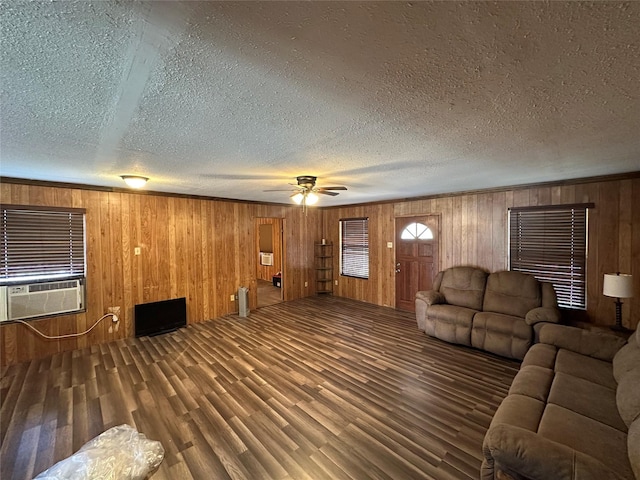 unfurnished living room with wood walls, cooling unit, dark hardwood / wood-style flooring, ceiling fan, and a textured ceiling