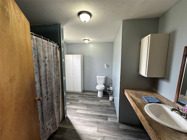 bathroom with hardwood / wood-style floors, sink, toilet, a textured ceiling, and a shower with shower curtain