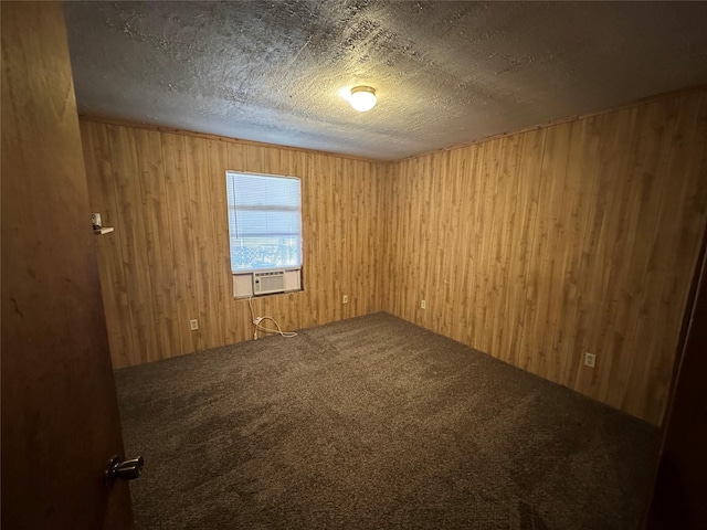 carpeted empty room with cooling unit, a textured ceiling, and wood walls