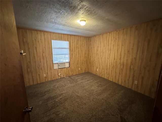 unfurnished room with cooling unit, wood walls, a textured ceiling, and carpet flooring