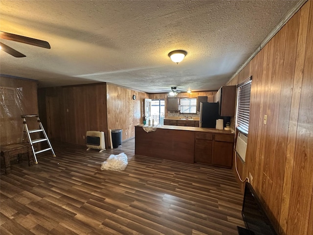 kitchen featuring stainless steel fridge, ceiling fan, dark hardwood / wood-style floors, heating unit, and kitchen peninsula