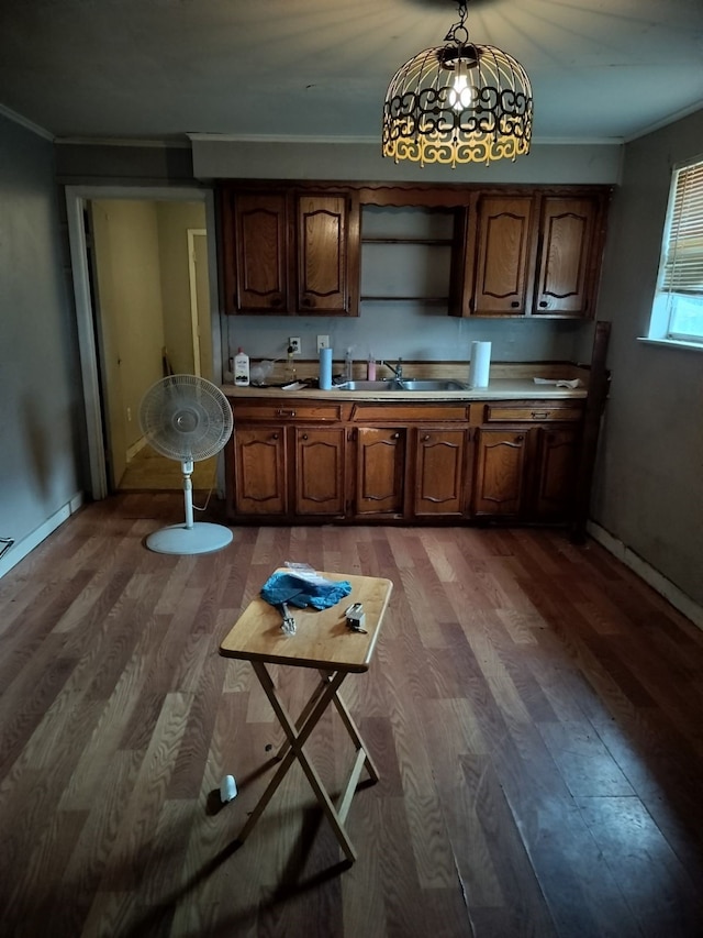 kitchen with decorative light fixtures, sink, hardwood / wood-style flooring, and crown molding