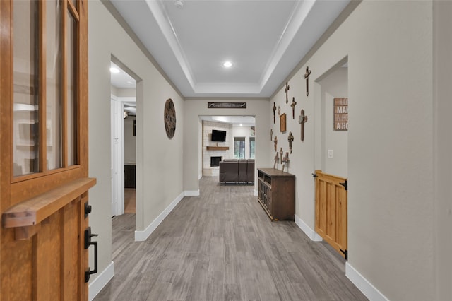 hallway with light hardwood / wood-style flooring and a tray ceiling