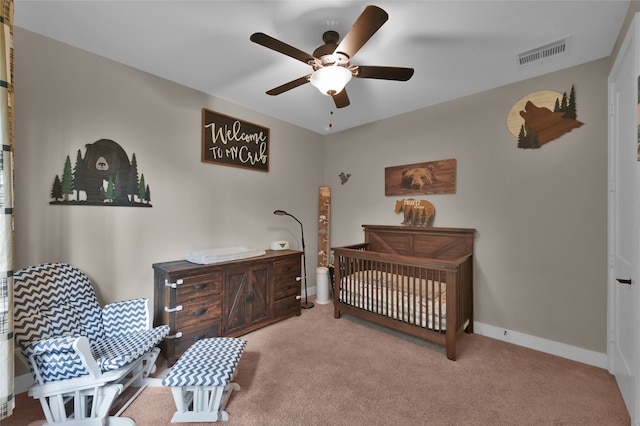 carpeted bedroom with ceiling fan and a nursery area