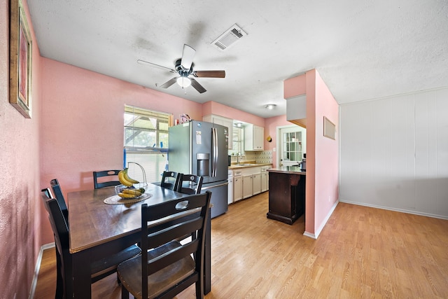 dining room with ceiling fan, sink, light hardwood / wood-style floors, and a textured ceiling