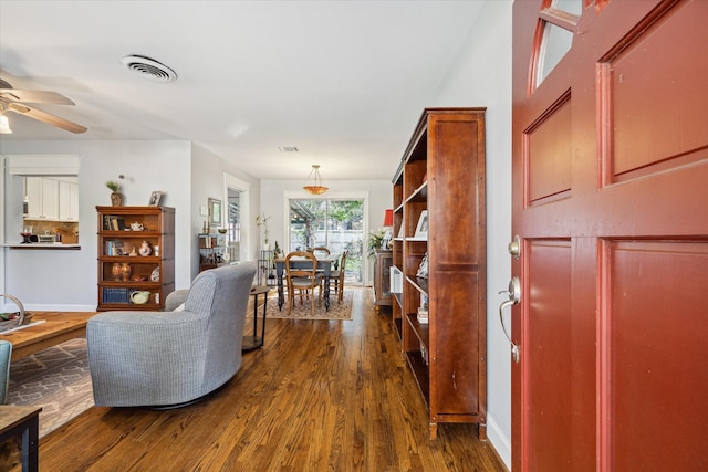 living room with ceiling fan and dark wood-type flooring