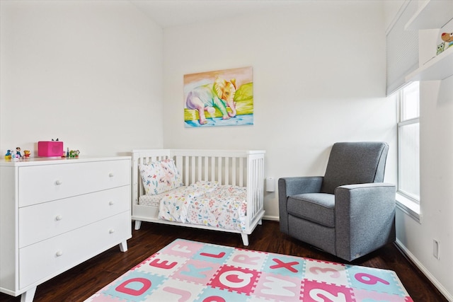 bedroom featuring dark hardwood / wood-style floors and a nursery area