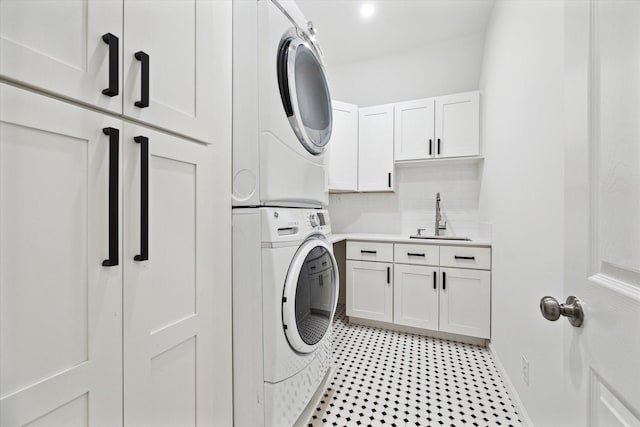 washroom with sink, stacked washer and clothes dryer, and cabinets