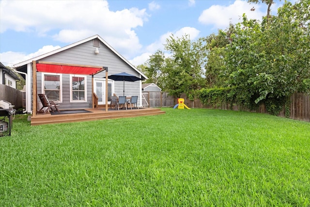 back of house with a yard, a wooden deck, and a playground