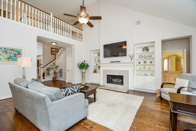 living room with built in shelves, high vaulted ceiling, and dark hardwood / wood-style flooring