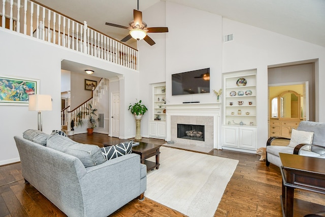 living area with baseboards, visible vents, stairway, wood finished floors, and a fireplace