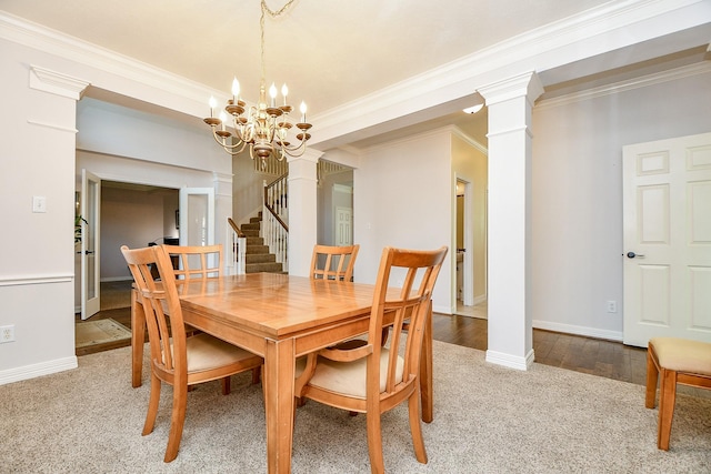 dining space featuring wood finished floors, decorative columns, baseboards, and stairs