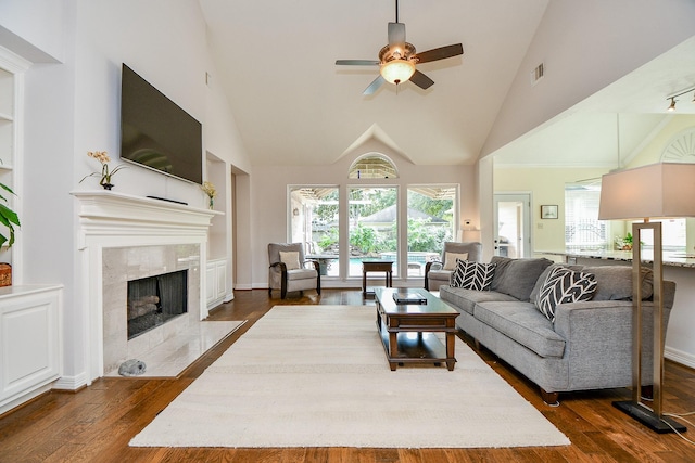 living area with visible vents, dark wood-style floors, ceiling fan, a fireplace, and high vaulted ceiling