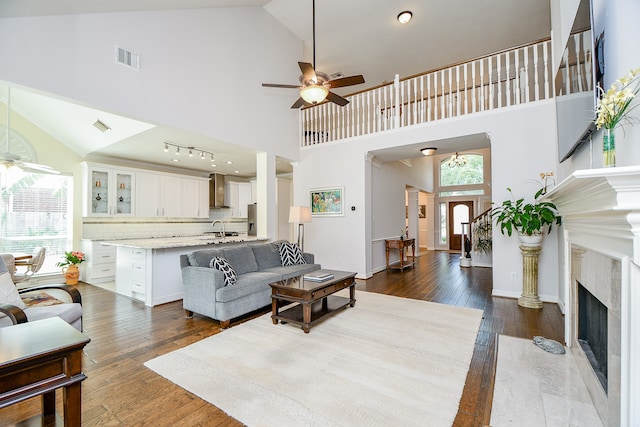 living room with high vaulted ceiling, dark wood-type flooring, ceiling fan, and a fireplace