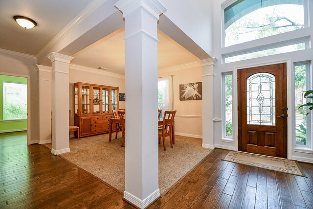 foyer entrance with crown molding, ornate columns, and dark hardwood / wood-style flooring