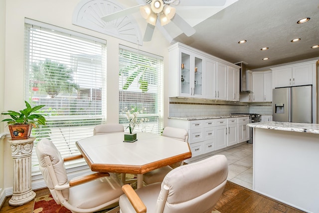 kitchen featuring decorative backsplash, white cabinetry, glass insert cabinets, and stainless steel fridge with ice dispenser