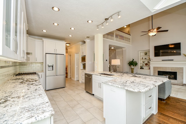 kitchen with stainless steel appliances, white cabinets, sink, a large island, and high vaulted ceiling