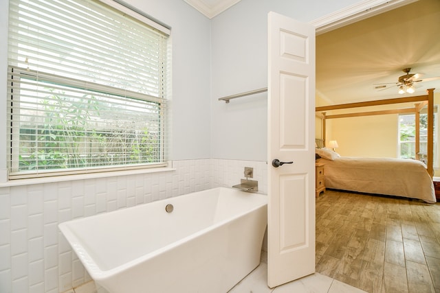 bathroom with a bathtub, ceiling fan, hardwood / wood-style floors, and ornamental molding