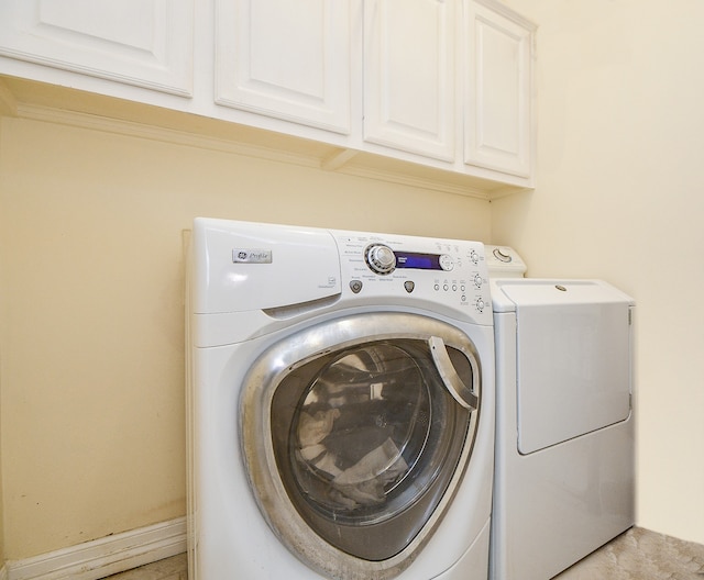 clothes washing area featuring washing machine and clothes dryer and cabinets