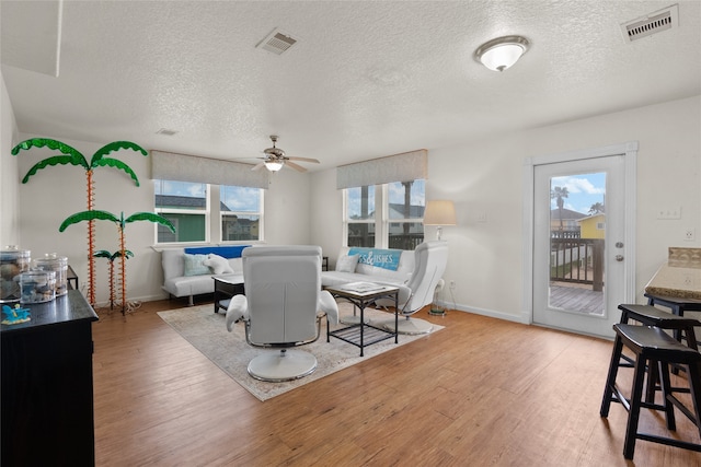 living room featuring ceiling fan, hardwood / wood-style floors, and a textured ceiling