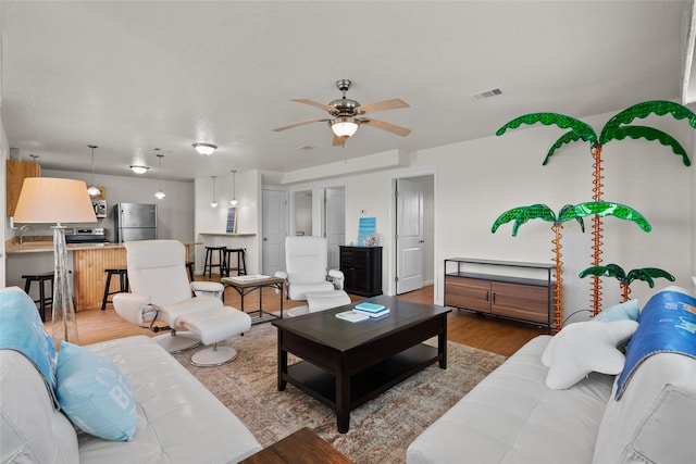 living room with light hardwood / wood-style flooring, ceiling fan, and sink