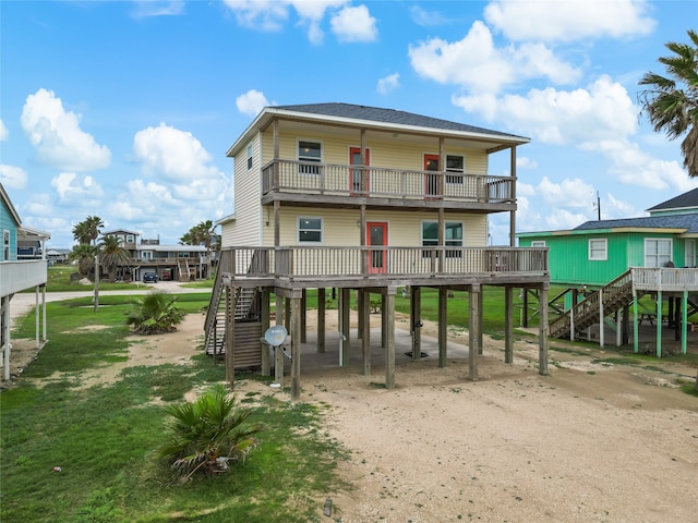 rear view of property featuring a lawn, a carport, and a balcony