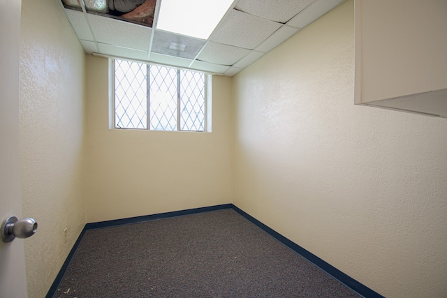 empty room featuring a paneled ceiling and carpet