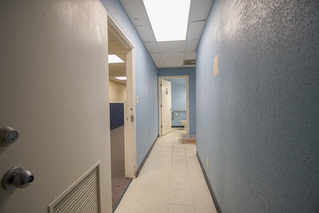 hall with a paneled ceiling