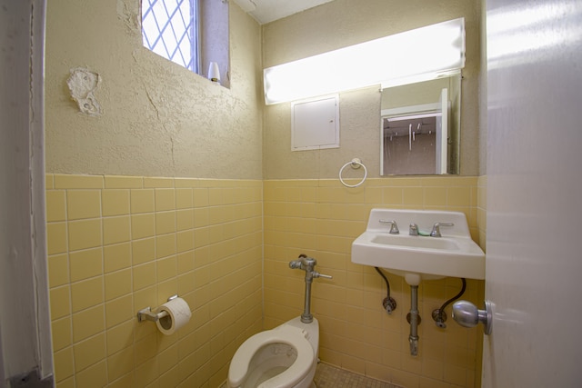 bathroom with toilet and tile walls