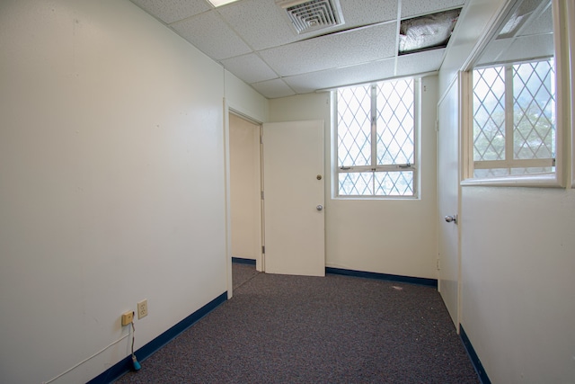 corridor featuring a paneled ceiling and dark carpet