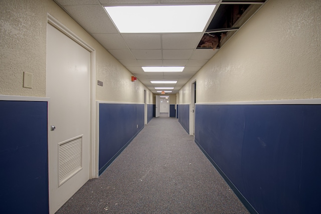 hallway with a paneled ceiling and carpet flooring