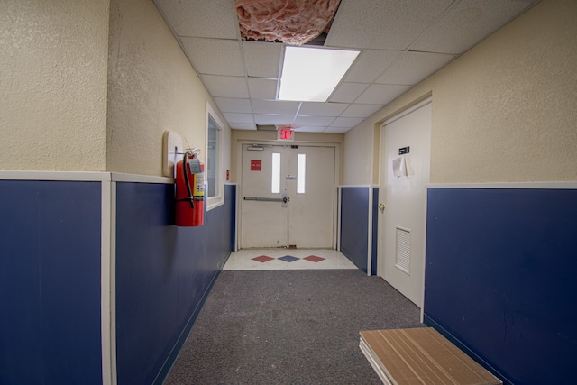 hall featuring a drop ceiling and carpet floors