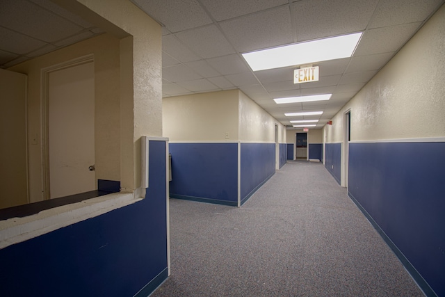 hall with a paneled ceiling and carpet