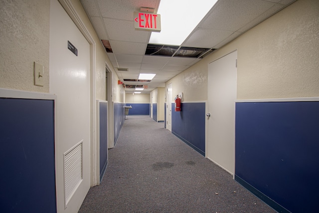 hall with a paneled ceiling and carpet