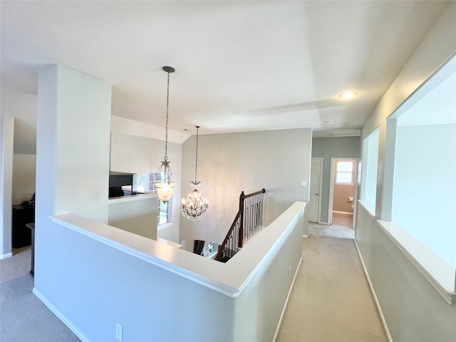 hallway featuring light carpet and an inviting chandelier