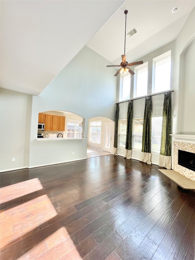 unfurnished living room featuring hardwood / wood-style floors, high vaulted ceiling, a wealth of natural light, and ceiling fan