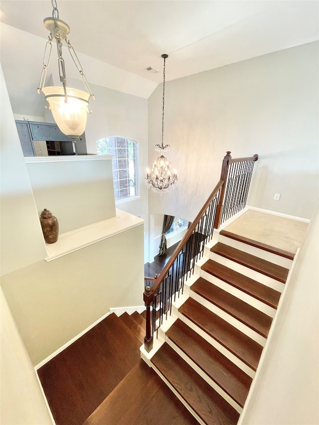 stairway with lofted ceiling and a chandelier