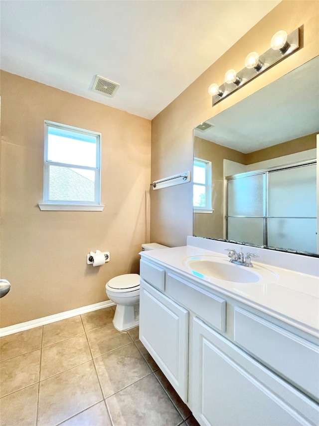 bathroom featuring toilet, vanity, tile patterned floors, and an enclosed shower