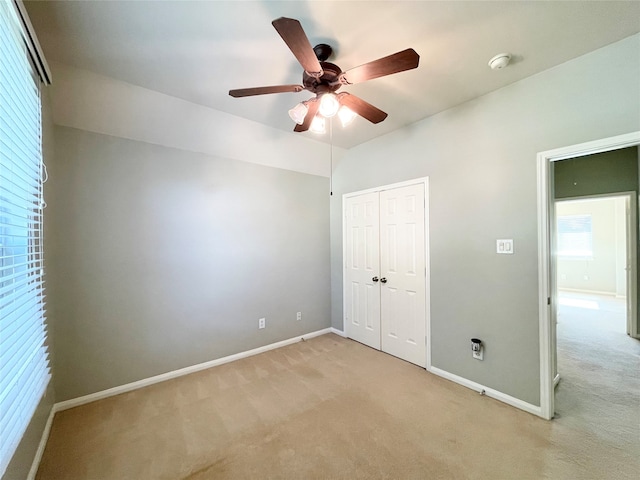 unfurnished bedroom with light carpet, a closet, and ceiling fan