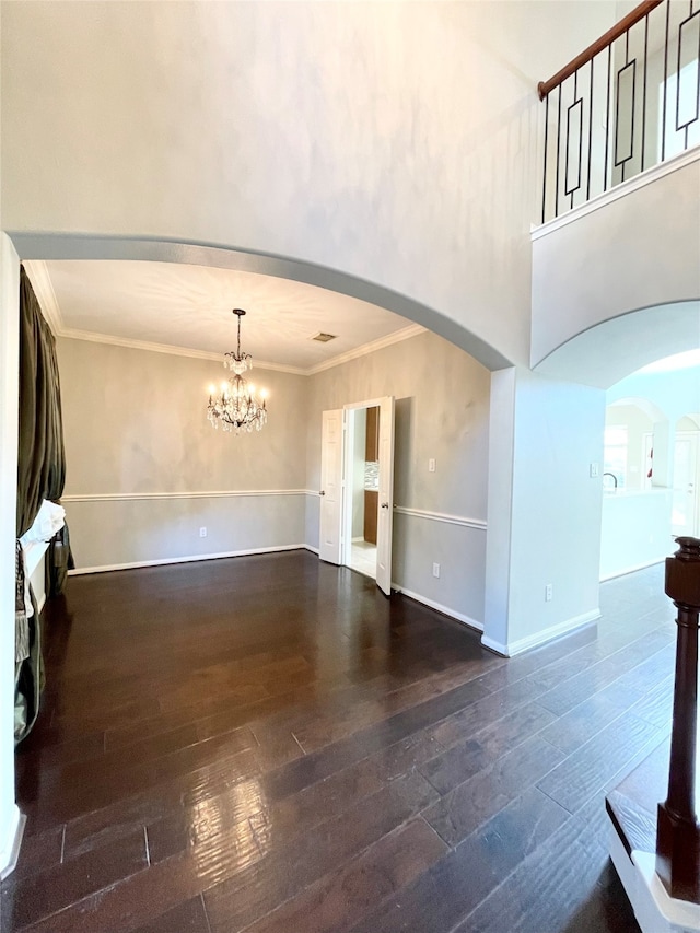 unfurnished living room featuring ornamental molding, dark hardwood / wood-style flooring, and a notable chandelier