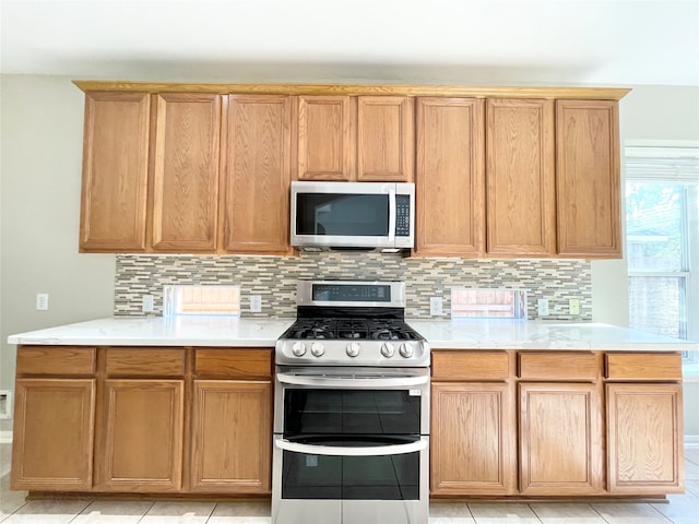 kitchen with decorative backsplash, light tile patterned flooring, and appliances with stainless steel finishes