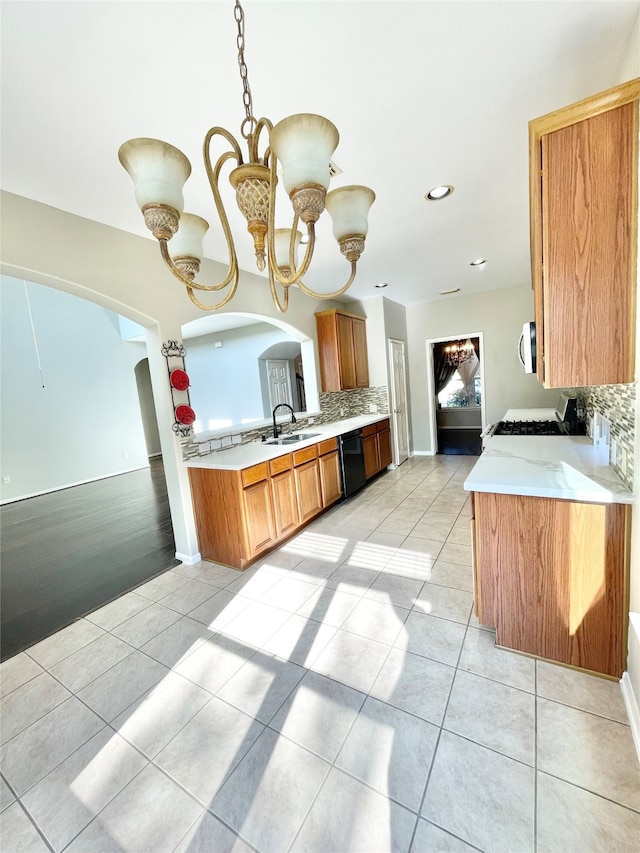 kitchen featuring dishwasher, sink, an inviting chandelier, kitchen peninsula, and decorative light fixtures