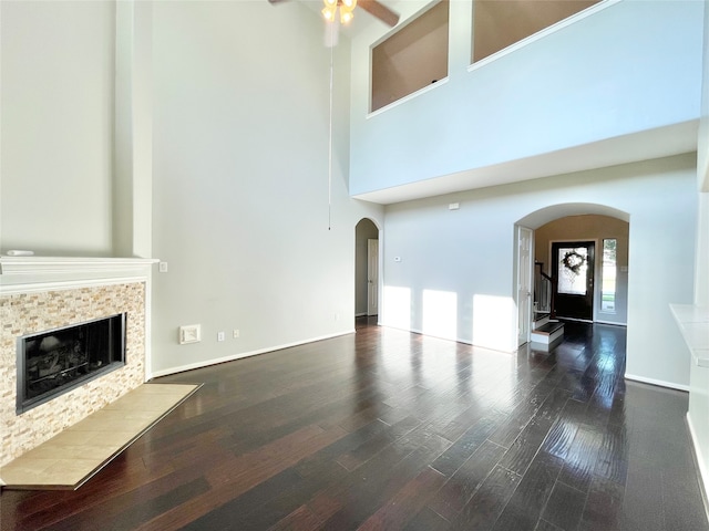 unfurnished living room with ceiling fan, dark hardwood / wood-style flooring, and a high ceiling