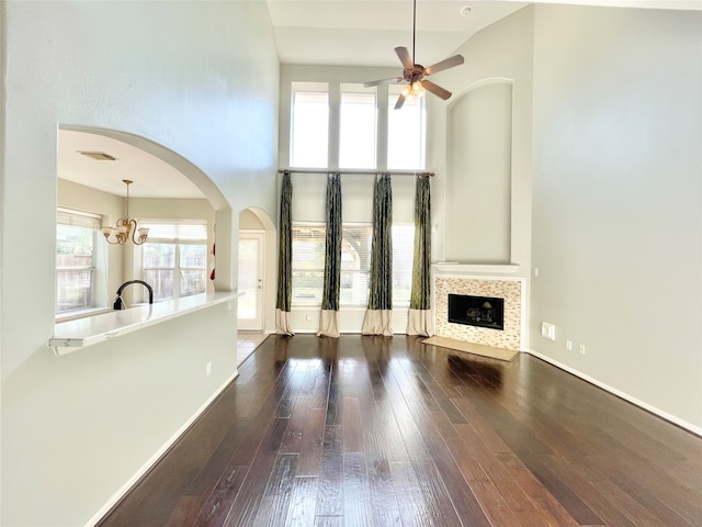 unfurnished living room featuring dark hardwood / wood-style floors, a tile fireplace, a wealth of natural light, and a towering ceiling