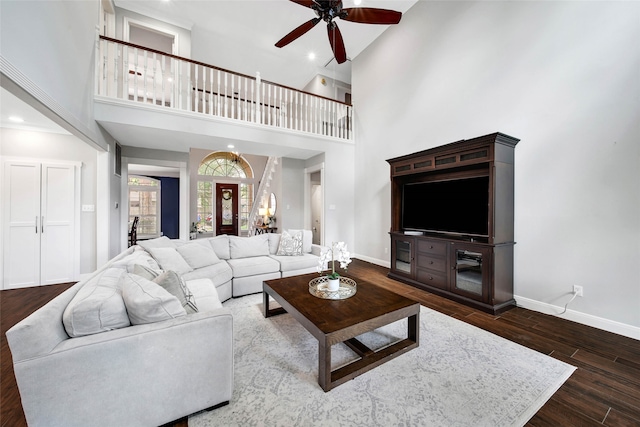 living room featuring hardwood / wood-style flooring, ceiling fan, and a towering ceiling