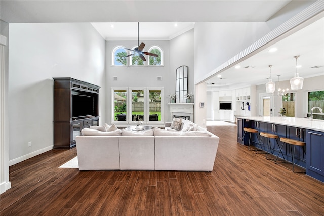 living room featuring dark hardwood / wood-style floors, ceiling fan, a towering ceiling, and crown molding