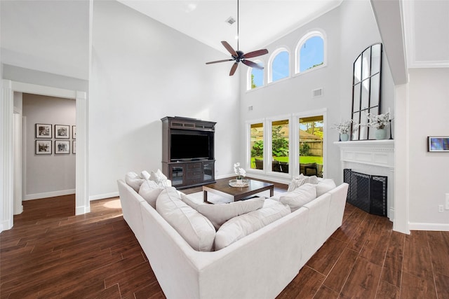 living room featuring dark wood-type flooring, a fireplace, visible vents, and baseboards